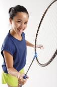 Woman holding badminton racket, smiling up at camera - Asia Images Group