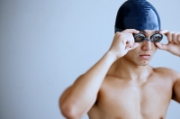 Man with swimming cap, adjusting goggles - Asia Images Group