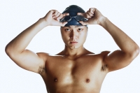 Man adjusting swimming goggles, looking at camera, portrait - Asia Images Group