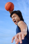 Man holding basketball in the air, mouth open - Asia Images Group