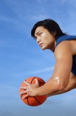 Man holding basketball, side view - Asia Images Group