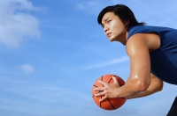 Man holding basketball, looking away, side view - Asia Images Group