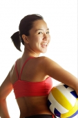 Woman carrying basketball, looking over shoulder at camera - Asia Images Group