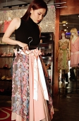 Woman in clothing store, holding skirt, looking down - Asia Images Group