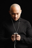 Man with shaved head, listening to music with earphones - Asia Images Group
