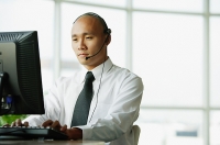Man with headset, using desktop PC - Asia Images Group