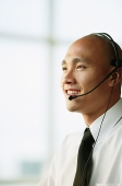 Man with headset, smiling, looking away - Asia Images Group