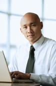 Man in front of computer, looking at camera, portrait - Asia Images Group
