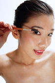 Woman applying mascara, looking at camera - Asia Images Group