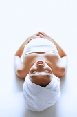 Woman wrapped in a towel, lying down, eyes closed - Asia Images Group