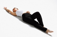 Woman lying on back, stretching - Asia Images Group