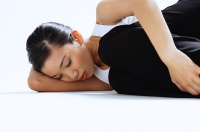 Woman lying on side, hugging knee, eyes closed - Asia Images Group