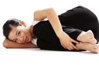 Woman lying on side, hugging knee, looking at camera - Asia Images Group