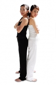 Two women standing back to back, arms crossed, looking at camera - Asia Images Group