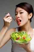 Woman eating from bowl of salad - Asia Images Group