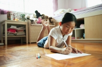 Girl in bedroom, lying on floor, drawing on paper - Asia Images Group