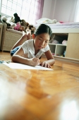 Girl in bedroom, lying on floor, writing on paper - Asia Images Group