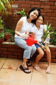 Mother and daughter, sitting, looking at camera - Asia Images Group