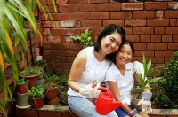 Mother and daughter, sitting in garden, looking at camera - Asia Images Group