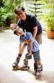 Father and son standing, wearing in-line skates, looking at camera - Asia Images Group