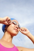 Woman adjusting swimming goggles, looking away - Asia Images Group