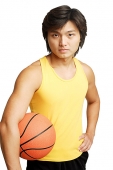 Man with basketball under arm, hand on hip, looking at camera, portrait - Asia Images Group