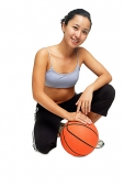 Woman crouching on floor, hand on basketball - Asia Images Group