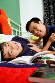 Father tickling son on bed - Asia Images Group