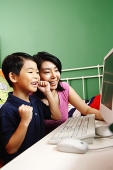Mother and son looking at computer, smiling - Asia Images Group