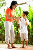 Mother and son standing, looking at terrapin - Asia Images Group