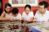 Family of four fixing jigsaw puzzle - Asia Images Group