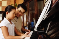 Daughter playing piano, father sitting next to her - Asia Images Group