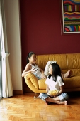 Two girls sitting in living room, talking - Asia Images Group