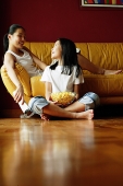 Two sisters sitting in living room, talking - Asia Images Group