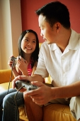 Father and daughter looking at each other, holding video game controllers - Asia Images Group