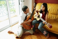 Father and daughter with guitars in living room - Asia Images Group