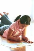 Girl lying on floor, drawing with crayons - Asia Images Group