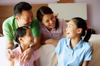 Father and mother with two daughters in bedroom - Asia Images Group
