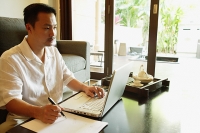 Man in living room, using laptop - Asia Images Group