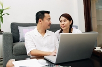 Couple in living room, with laptop - Asia Images Group