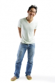 Young man in T-shirt and jeans, standing, smiling at camera - Asia Images Group