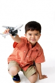 Boy holding toy airplane, looking at camera - Asia Images Group