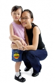 Young girl standing, mother crouching next to her, looking at camera - Asia Images Group