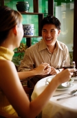 Man holding woman's hand in restaurant, ring on her finger - Asia Images Group