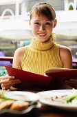 Woman in cafe, holding menu, looking at camera, smiling - Asia Images Group
