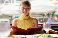 Woman holding menu, looking at camera, smiling - Asia Images Group
