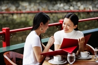 Women in cafe, looking at menu, laughing - Asia Images Group