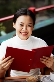 Women in cafe, holding menu, smiling at camera - Asia Images Group