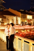 Couple kissing on bridge, woman holding roses - Asia Images Group