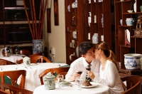 Couple sitting in restaurant, kissing - Asia Images Group